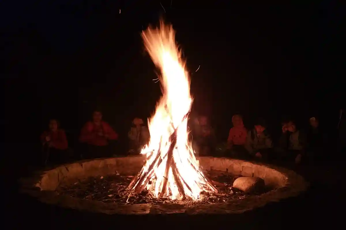 Lagerfeuer im Ostercamp von Wildnispfade, umgeben von Kindern, die Geschichten lauschen und die Wärme der Flammen genießen.