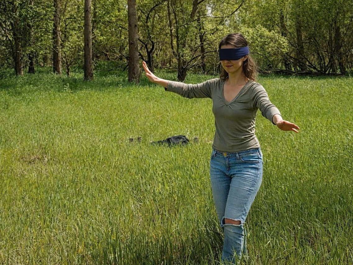 Eine Frau läuft blind durch die Natur.