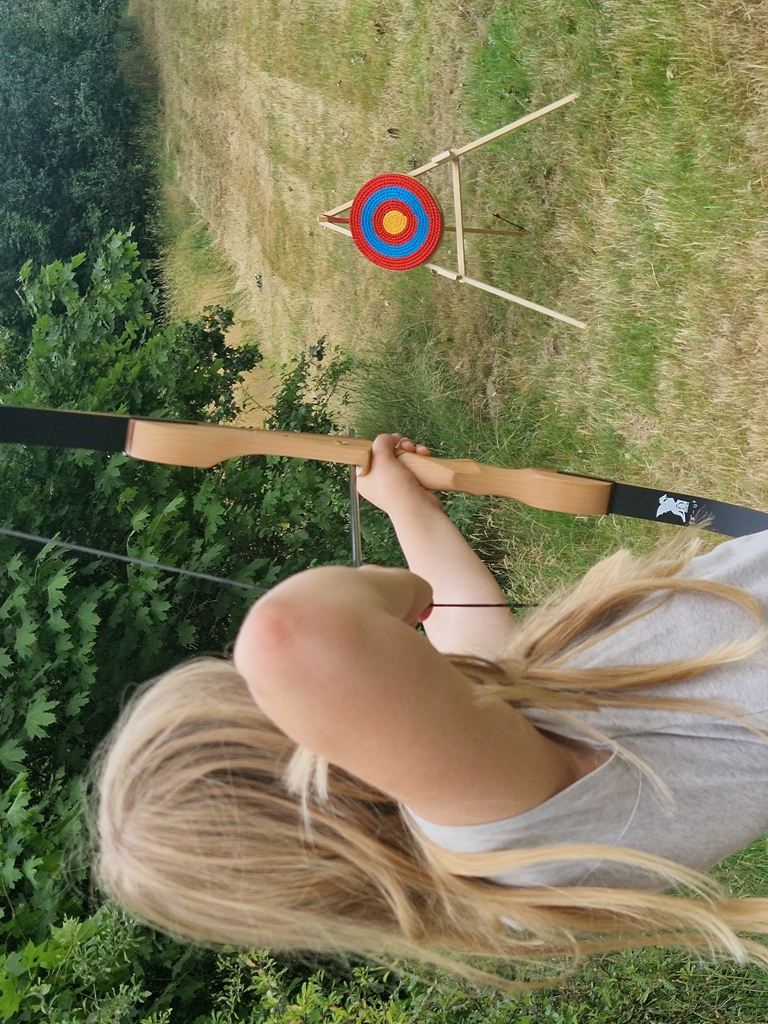 Ein Mädchen schießt mit dem Bogen beim wilden Projekttag an ihrer Schule.